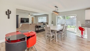 Un vaste espace de vie comprenant une table à manger, des chaises rouges, un téléviseur et un ventilateur de plafond.