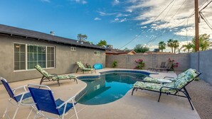 Un jardin avec une piscine, des chaises longues et une table de patio.