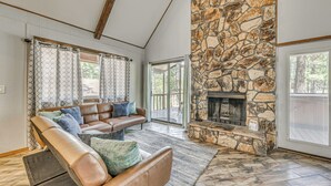 A spacious living room with a stone fireplace, leather sofas, and a large window.