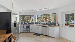 A modern kitchen with stainless steel appliances, white cabinetry, and large windows offering views of trees. - Boaters Paradise W Dock Access - .4 Mile to Beach (Englewood)