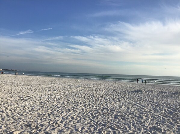A wide sandy beach with gentle waves and a clear sky.