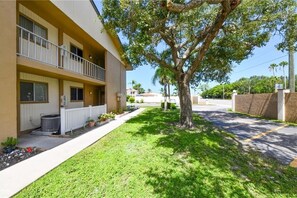 Situated in a residential area, this two-story building features a balcony and a well-manicured lawn with a mature tree.