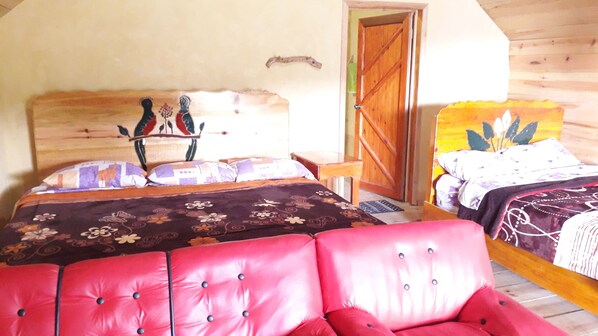 Un dormitorio con dos camas, una puerta de madera y una silla roja.