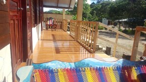 A wooden deck with a tiled floor, a colorful woven mat, and a view of the surrounding area. - Cabanas Islas de Tziscao (La Trinitaria)