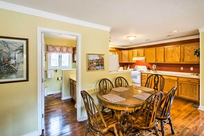 A dining area with a wooden table and chairs, a kitchen with wooden cabinets, and a hallway leading to a bathroom. - Damascus Apt w/ Views, Walk to Shops + Parks! (Damascus)