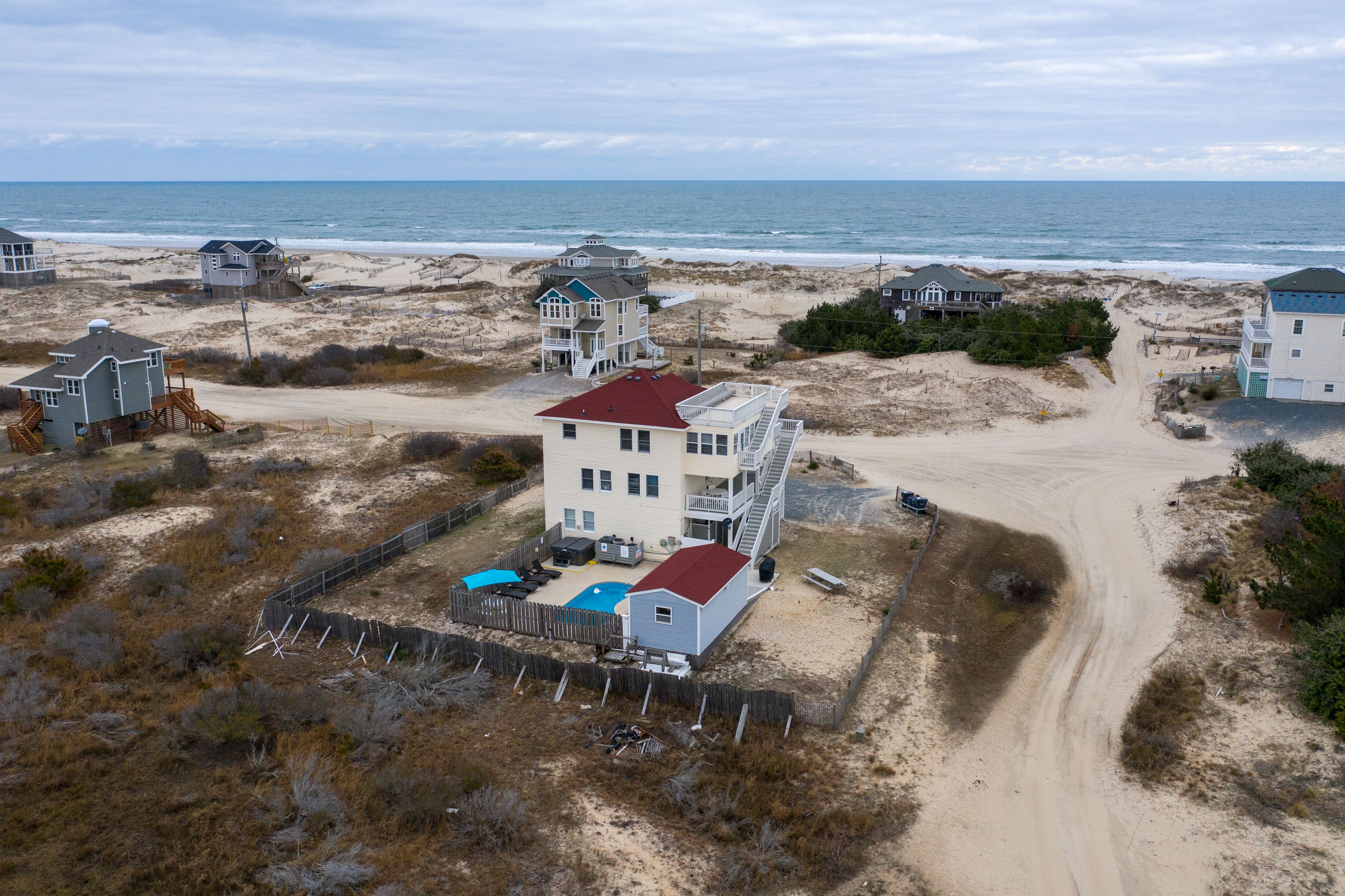 Une propriété située en bord de mer, comprenant plusieurs maisons, une plage de sable et une vue dégagée sur l’océan.