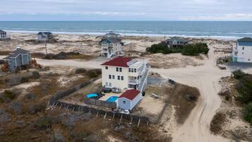 Une propriété située en bord de mer, comprenant plusieurs maisons, une plage de sable et une vue dégagée sur l’océan.
