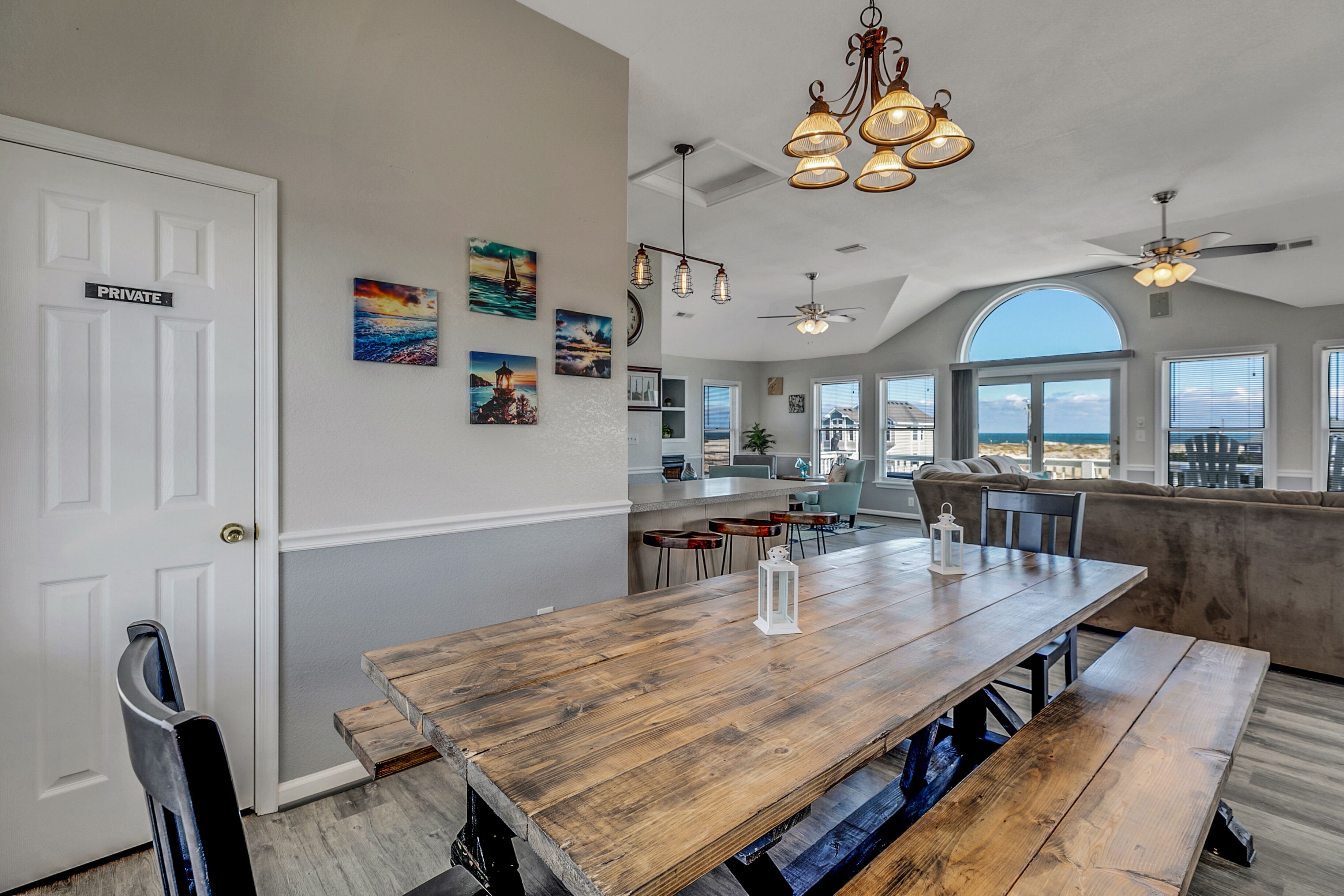 A spacious kitchen with a wooden table, pendant lights, and a view to the outside.