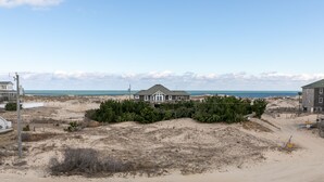 Una propiedad frente a la playa con una casa grande, dunas arenosas y una vista despejada del océano.