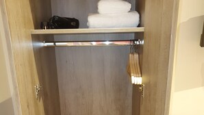 Ein Holzschrank mit einer Ablage für Handtücher und einer Kleiderstange.