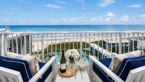 A balcony with a view of the beach, a bottle of wine, and a vase of flowers. - Sapphire 1505 - By GISO Vacation Rentals (South Padre Island)