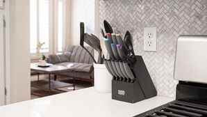 A kitchen with a knife block on the counter, a white countertop, and a herringbone-patterned backsplash.