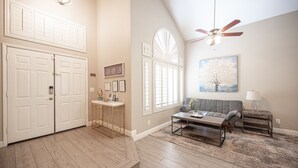 A spacious living room with a gray sofa, coffee table, and a ceiling fan.