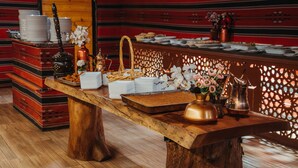Una mesa de madera con platos, una cesta de pan y un jarrón de flores.