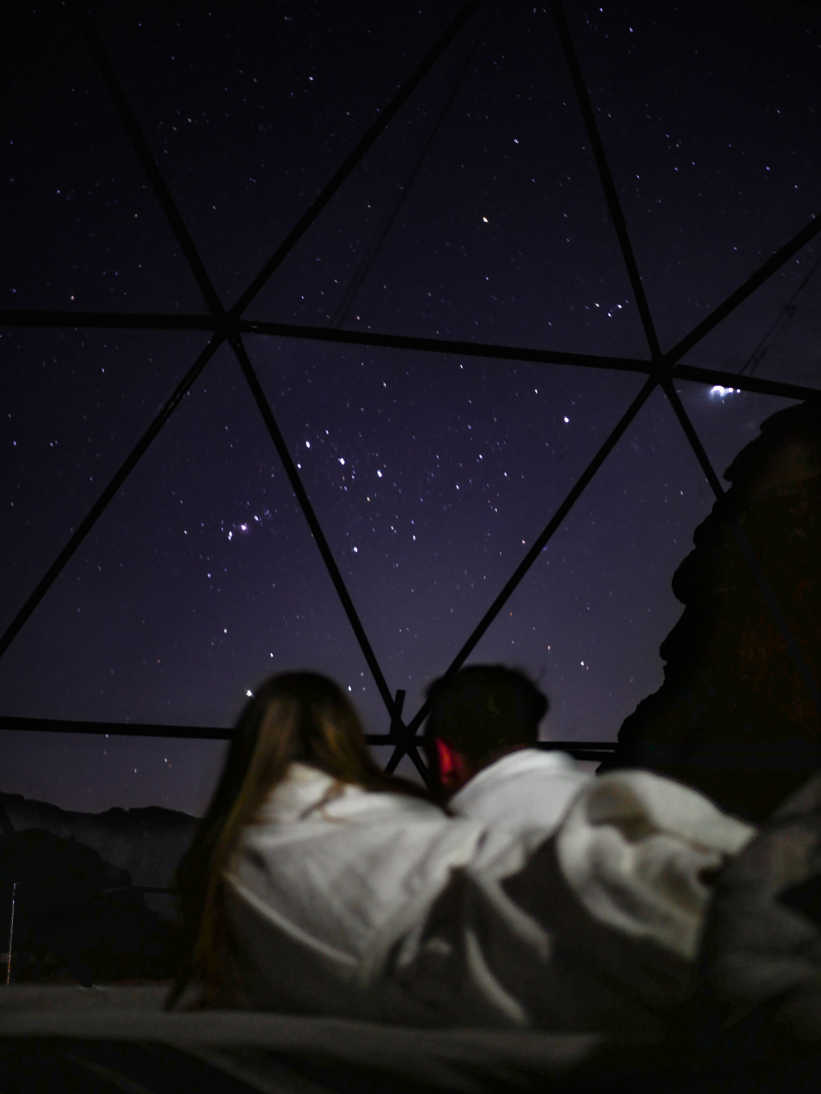 Un ciel étoilé observé à travers une structure de verre aux formes géométriques.