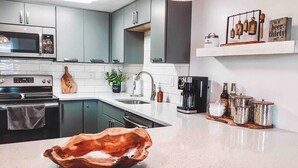 Una cocina moderna con gabinetes grises, electrodomésticos de acero inoxidable y un original cuenco de madera como centro de mesa.