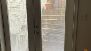 Une pièce dotée d’une porte à deux battants avec des panneaux en verre dépoli, d’un paillasson vert et d’un sol carrelé.