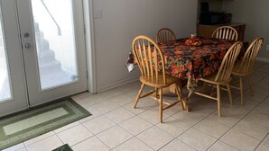 Un coin repas avec une table recouverte d’une nappe à motifs floraux, entourée de chaises en bois.