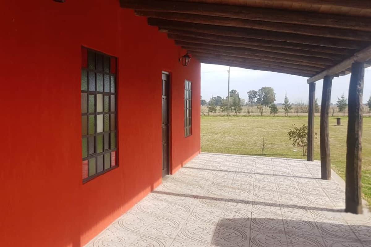 A red building with a covered porch and a view of a grassy field.