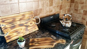 A kitchen with a gas stove, a kettle, a wooden cutting board, and a potted plant. - La Maina Uribe Posada y Cabañas (Lobos)