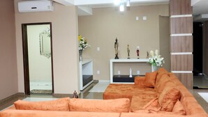 A living room with a sofa, a white console table with decorative items, and a ceiling light fixture. - Amazonia Palace Hotel (Maraba)