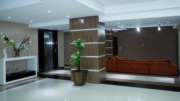 A modern lobby with a reception desk, a potted plant, a sofa, and an elevator. - Amazonia Palace Hotel (Maraba)