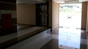A spacious lobby with a modern design, featuring a large glass door leading outside, a red door, and a tiled floor. - Amazonia Palace Hotel (Maraba)