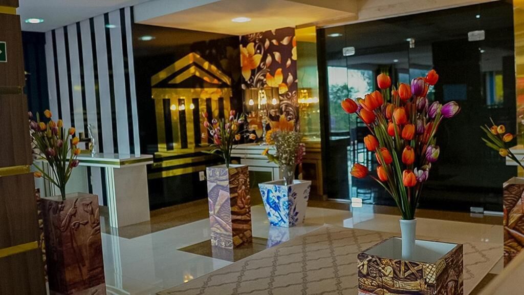 A reception area with a modern design, featuring a reception desk, decorative vases with flowers, and a patterned floor.