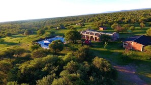 A rural property with a large house, a swimming pool, and surrounding greenery.