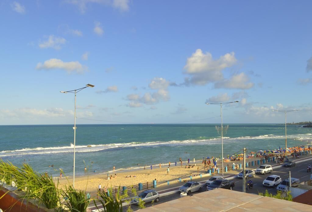 A beach view with a road and parked cars.