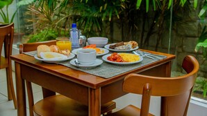 A dining table with breakfast items, including eggs, toast, and orange juice, set against a backdrop of lush greenery. - Brisa do Mar Beach Hotel (Natal)