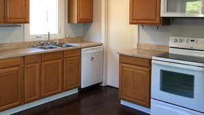 Una cocina con armarios de madera, lavavajillas, microondas y horno.