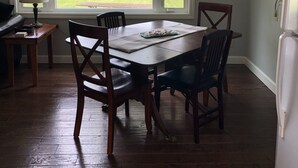 Un comedor con una mesa, sillas, una lámpara y vistas a una masa de agua a través de amplios ventanales.