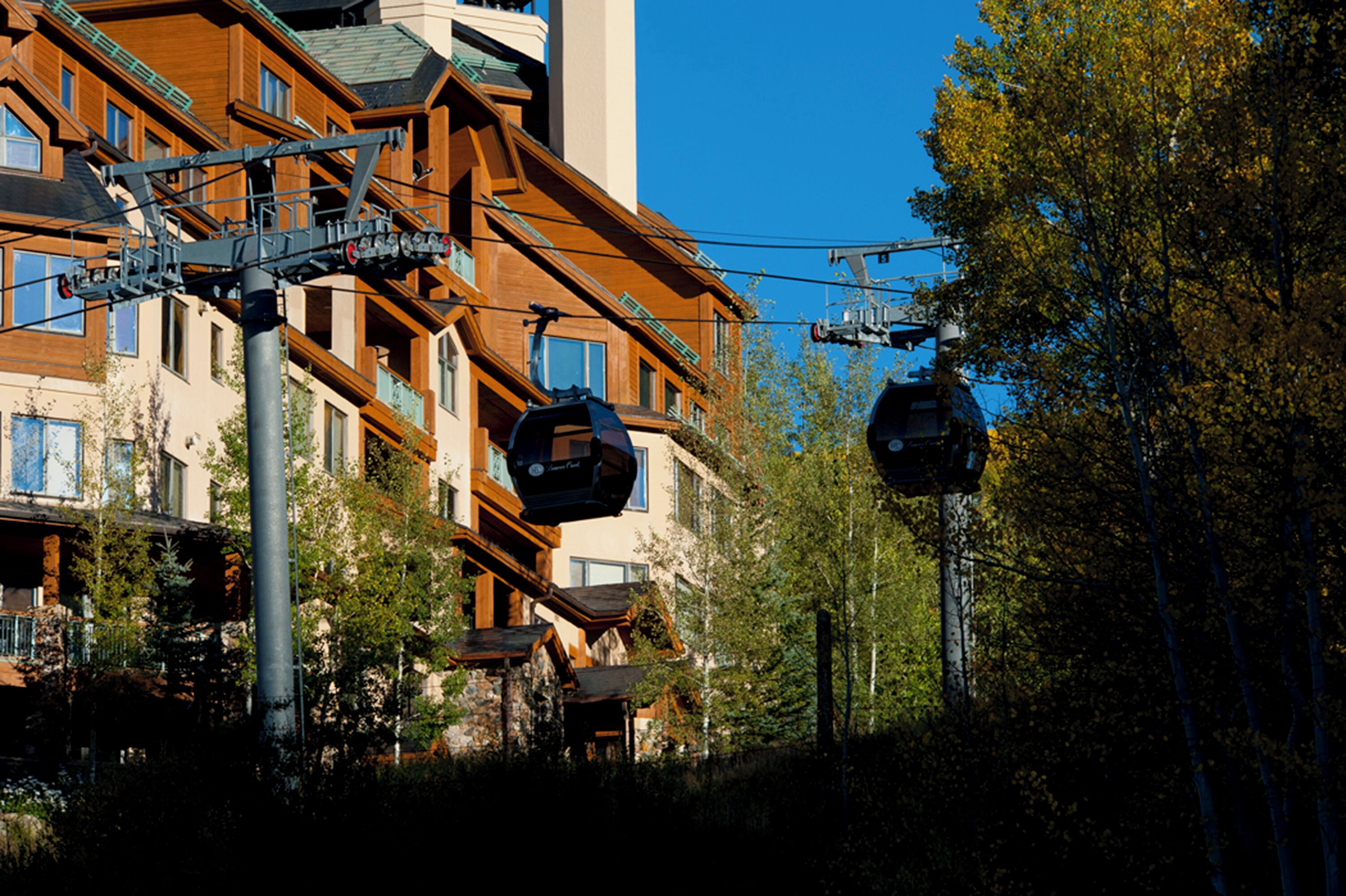 A multi-story building with a ski lift system, surrounded by trees and greenery.