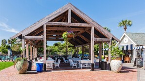 Un pavillon en bois, doté de tables et de chaises, entouré de vélos et de plantes en pot.