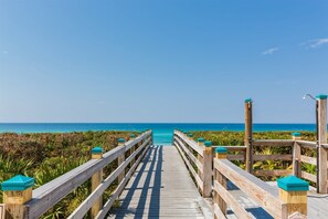 A wooden boardwalk leading to a beach with a clear view of the ocean.