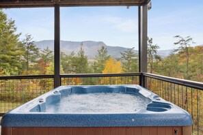 A hot tub in a covered outdoor area with a view of mountains and autumn trees. - Cabin w/Amazing Mountain Views-Theater-Game Room (GATLINBURG)