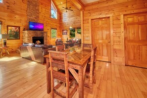 A log cabin interior with a fireplace, wooden furniture, and a stone wall.