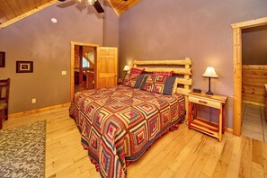 A bedroom with a wooden bed, a nightstand, a lamp, and a door leading to another room. - Cabin w/Amazing Mountain Views-Theater-Game Room (GATLINBURG)