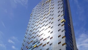 Ein hohes Gebäude mit modernem Design, das ein Gitter aus Fenstern und Balkonen zeigt.