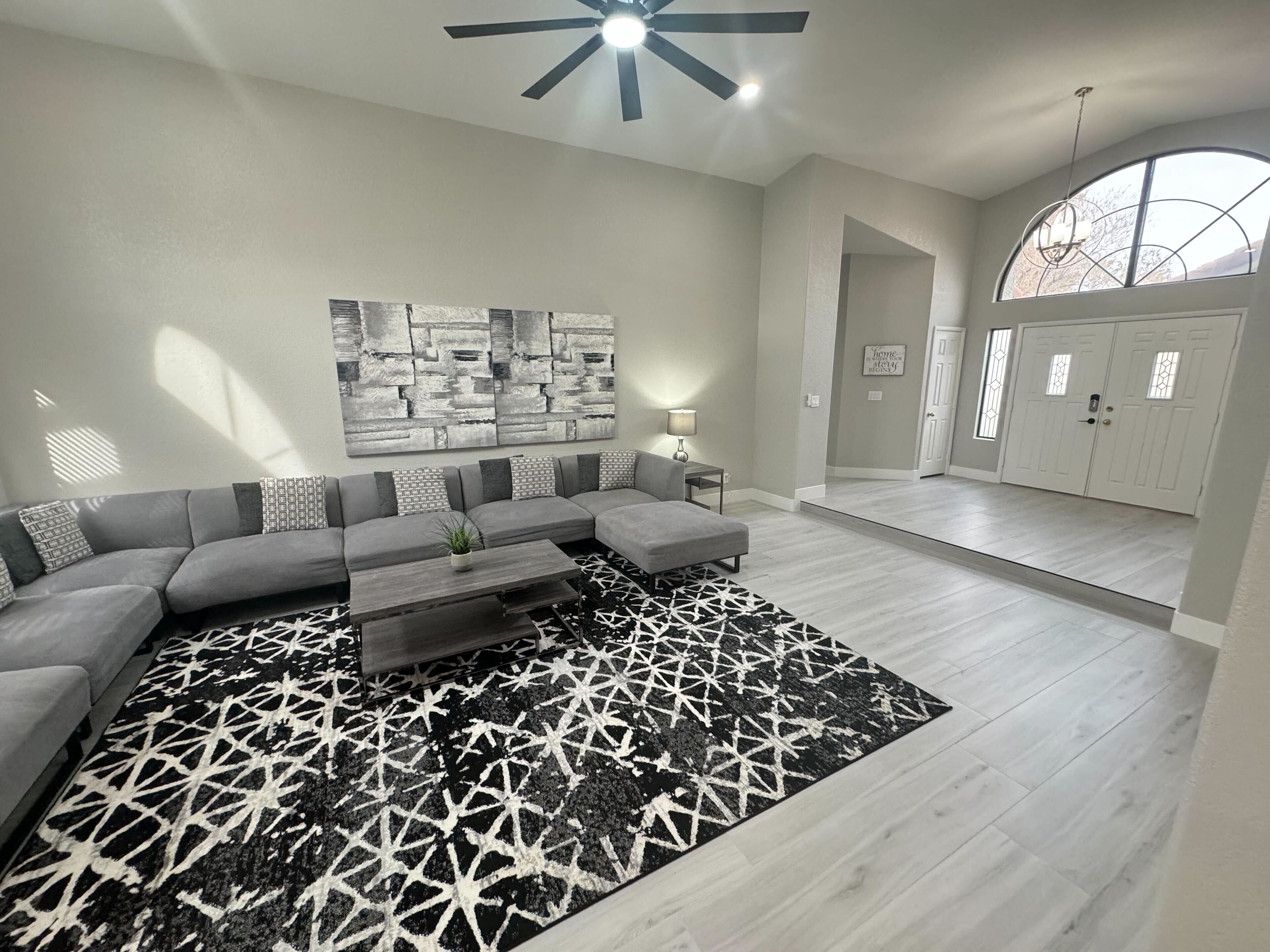Un salon moderne avec un canapé d’angle, une table basse et un tapis à motifs.