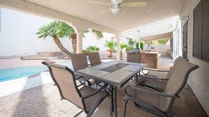 Une terrasse extérieure avec une piscine, des espaces salon couverts et un ventilateur de plafond.