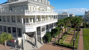 A large, multi-story building with balconies, a covered porch, and a central staircase.
