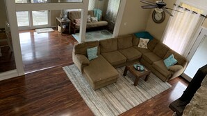 A spacious living room with a sectional sofa, a wooden coffee table, and a ceiling fan. - Waterfront Home! Relax & Enjoy the Serenity of Lake Palestine.  
 (Chandler)