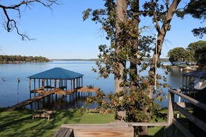 Una propiedad frente al lago con un muelle de madera, una zona de estar cubierta y un pabellón.