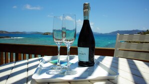 Una botella de Prosecco y dos copas sobre una mesa con vista panorámica al océano.