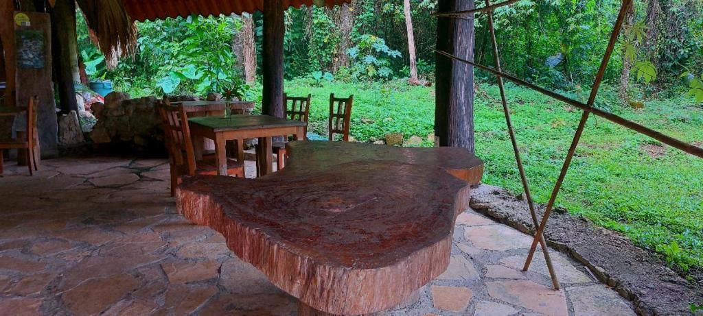 A rustic wooden table and chairs set on a stone patio with a natural backdrop.