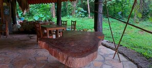 Un conjunto de mesa y sillas de madera rústica en un patio de piedra con un entorno natural.