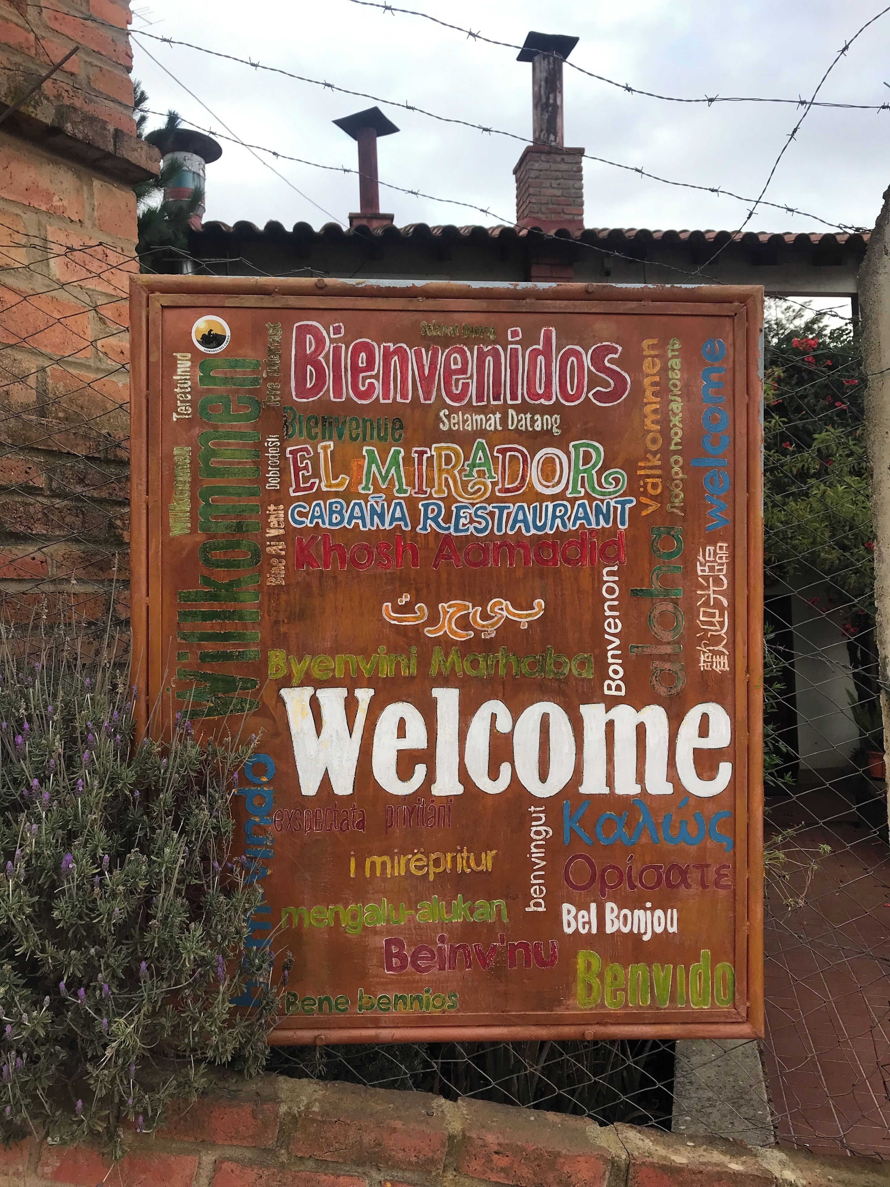 Une enseigne accueillante avec des messages de bienvenue dans plusieurs langues et le nom d’un restaurant.