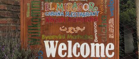 Un letrero de bienvenida con saludos en varios idiomas y el nombre de un restaurante.